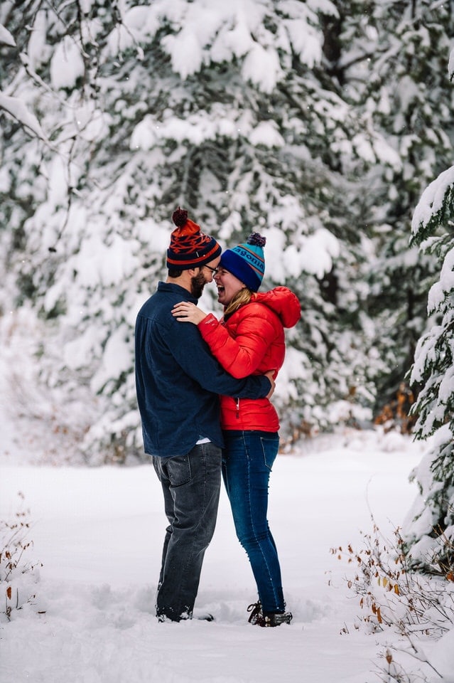 Couple laughs together during their snowy engagement session in McCall, Idaho.