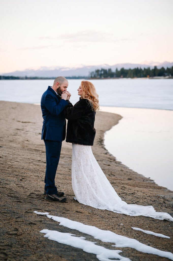 A groom warms his brides hands during their elopement at an Airbnb cabin in McCall, Idaho.
