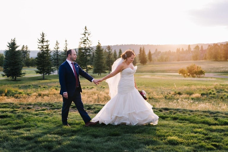 River Ranch is McCall, Idaho wedding venue. Bride and groom walk together at sunset in front of the River Ranch clubhouse.