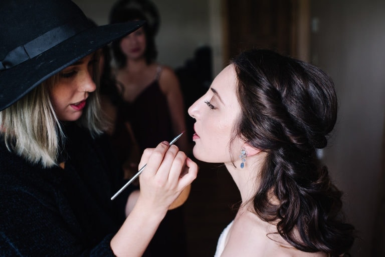 Bride gets her makeup touched up during a wedding day at Moonridge Cabin in McCall, Idaho.