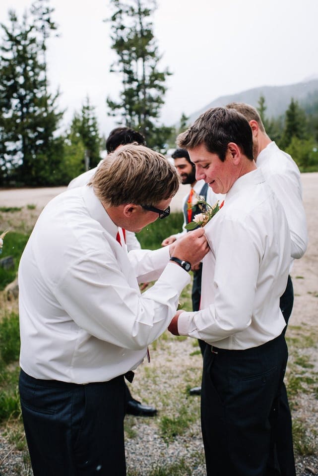 Groomsmen putting on boutonnieres during a Redfish Lake Lodge Wedding in Stanley, Idaho.