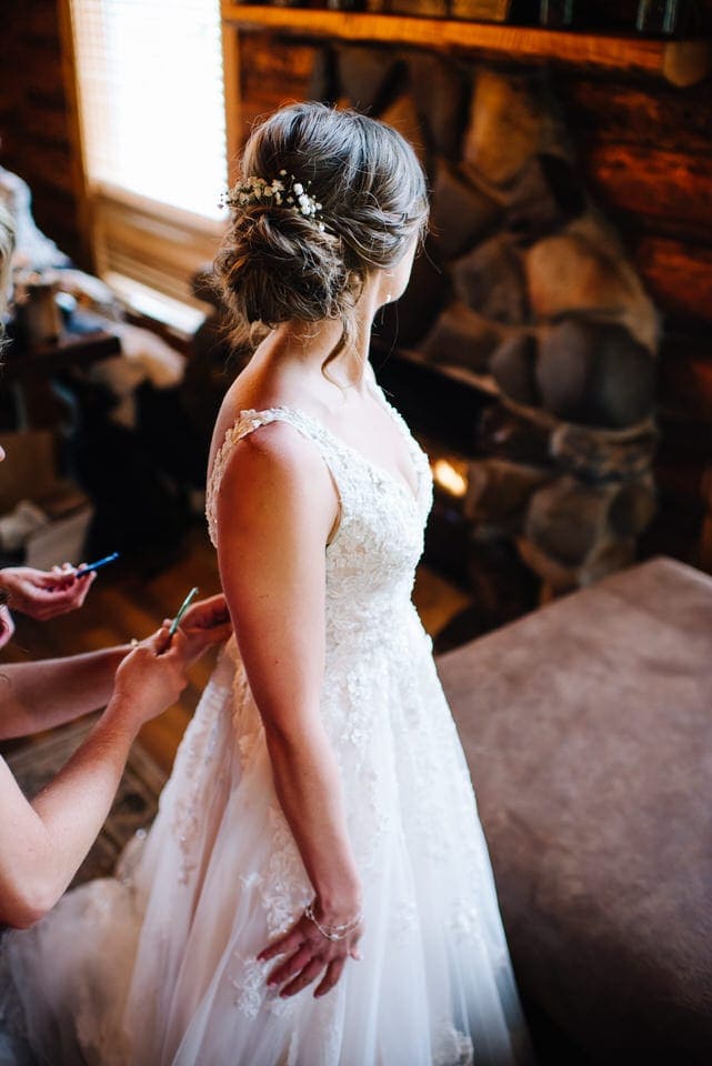 Bride dress being buttoned up during a Redfish Lake Lodge Wedding in Stanley, Idaho.