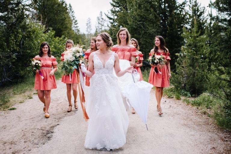 Bride leads bridal party through pine trees during a Redfish Lake Lodge Wedding in Stanley, Idaho.
