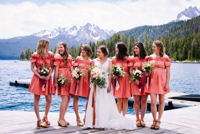 Bridal party stands together on the redfish Lake Lodge dock in Stanley, Idaho with the sawtooth mountains behind them during a Redfish Lake Lodge Wedding.