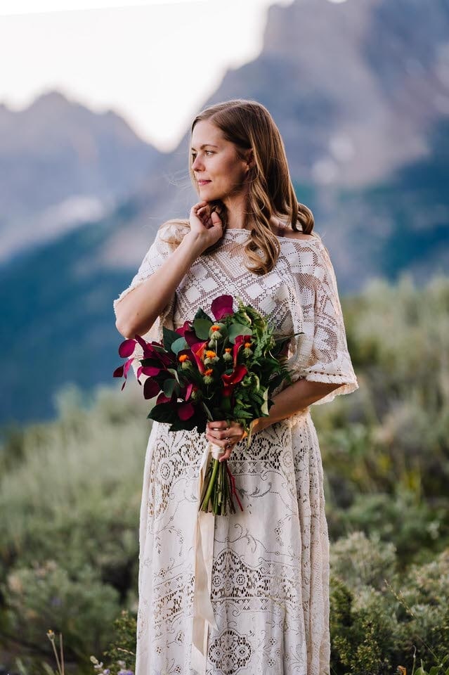 Bride holds a bouquet of red and orange flowers from a Stanley, Idaho florist.