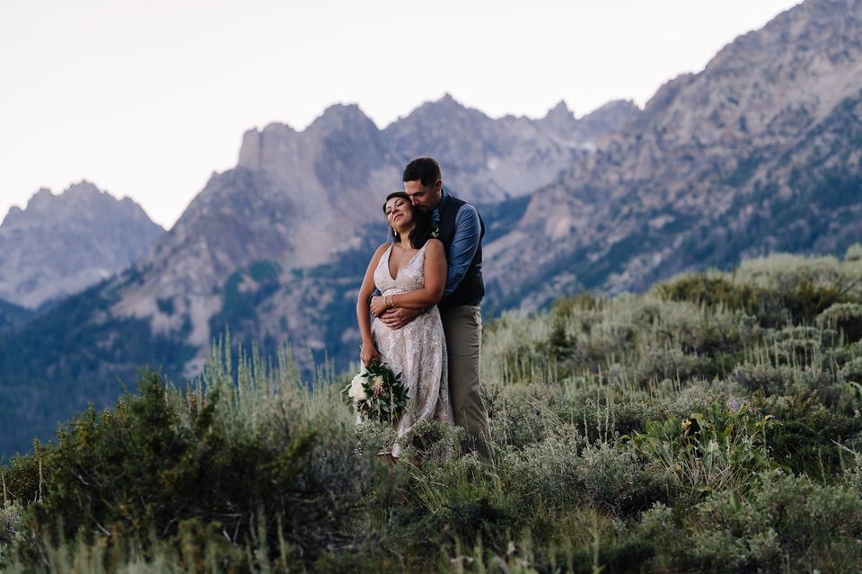 Couple embraces, with mountains behind them, during their Stanley, Idaho elopement.