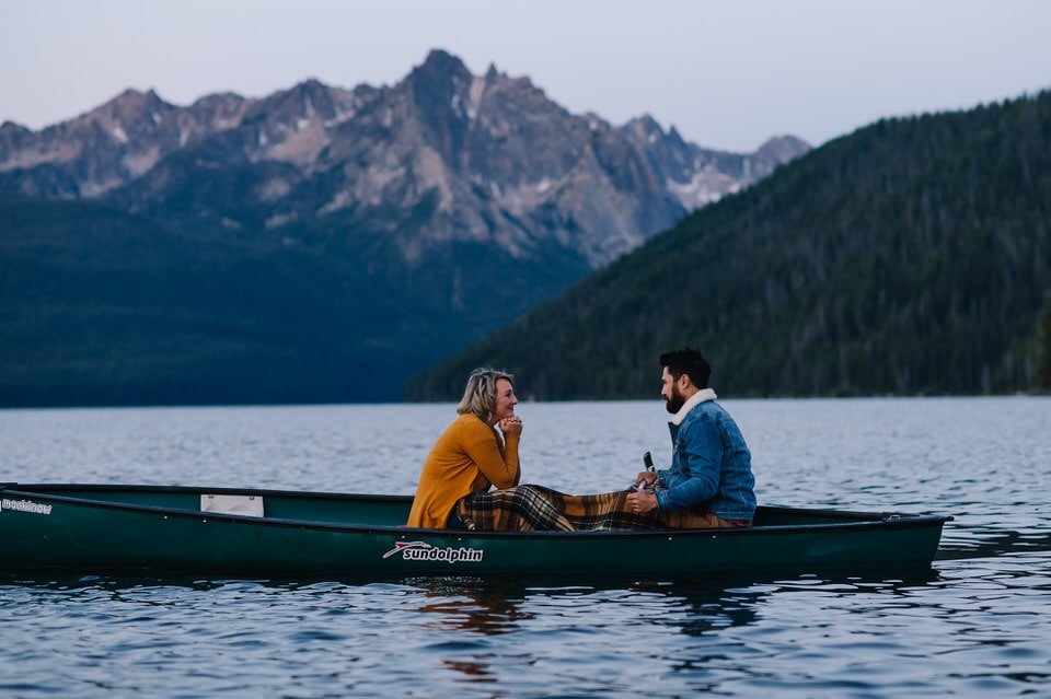 Couple canoes at sunrise on Redfish Lake during their engagement session in Stanley, Idaho.