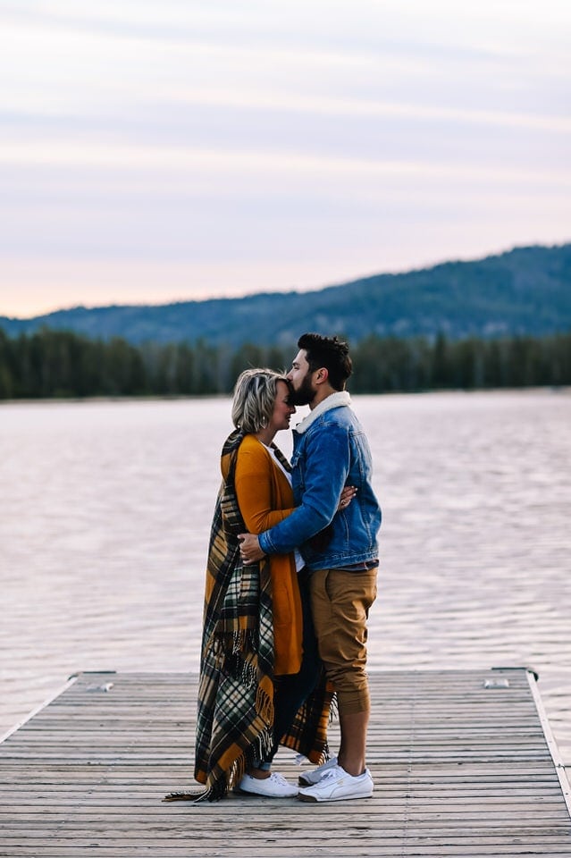 Engaged couple embraces on a dock at Redfish Lake in Stanley, Idaho during their engagement session.