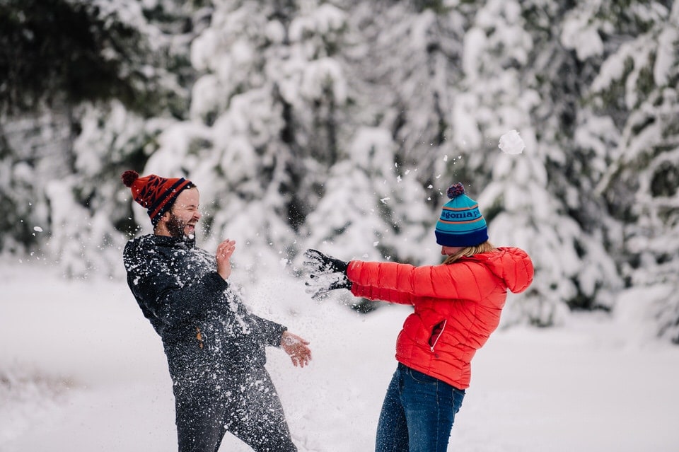 Couple throws snowballs during their snowy engagement session in McCall, Idaho.