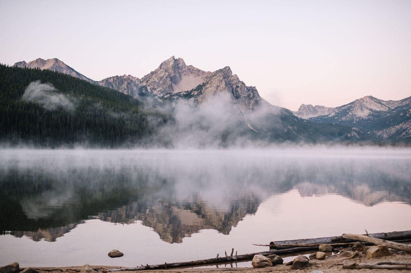 Landscape photo of an Idaho mountain lake at sunrise. Mist is rising off the lake and the mountains are reflected in the water. Idaho is one of the easiest states to get married in.