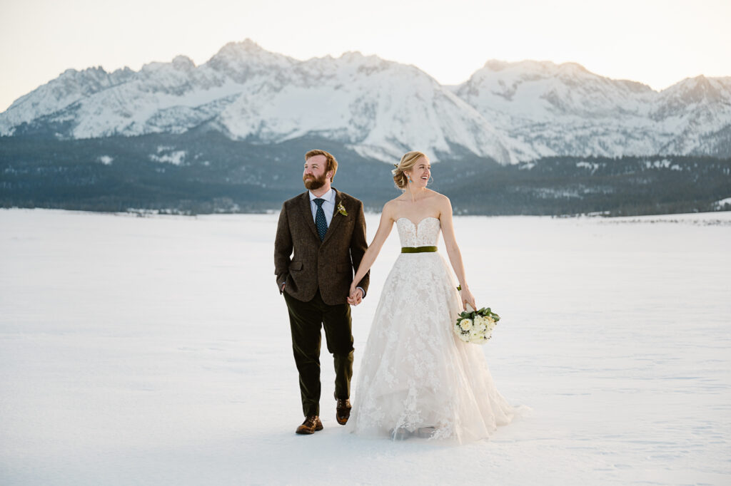A couple walks across a snow covered field during their Idaho elopement package with Autumn Lynne Photography.