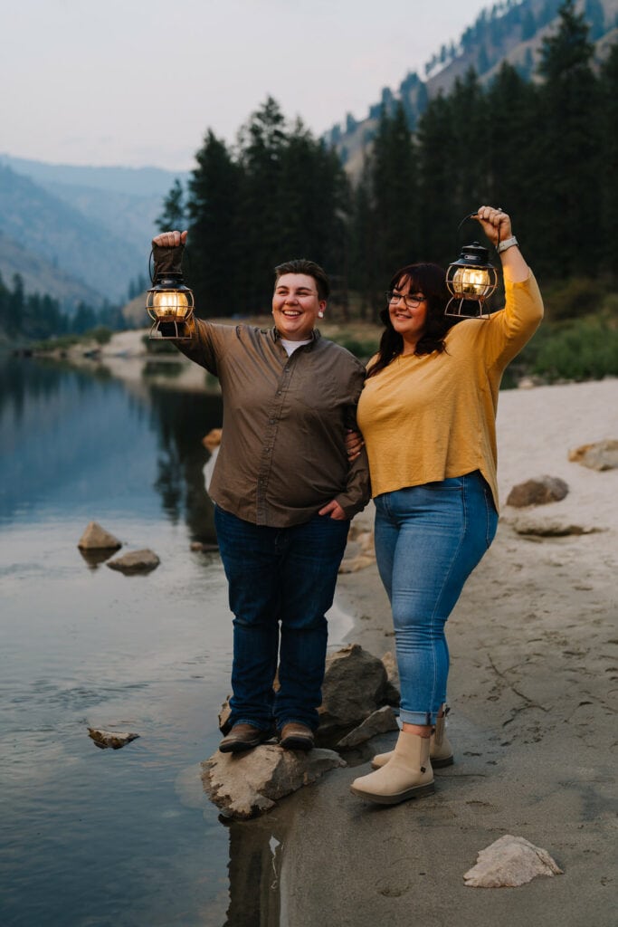 A couple stands together holding lanterns at dusk. This couple had engagement photos taken in Riggins, Idaho.